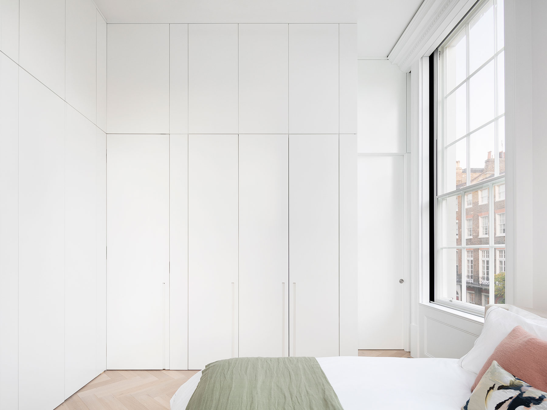 A master bedroom with extensive full height storage integrated seamlessly with complimentary panelling and doorways both out of the room and into an en suite space