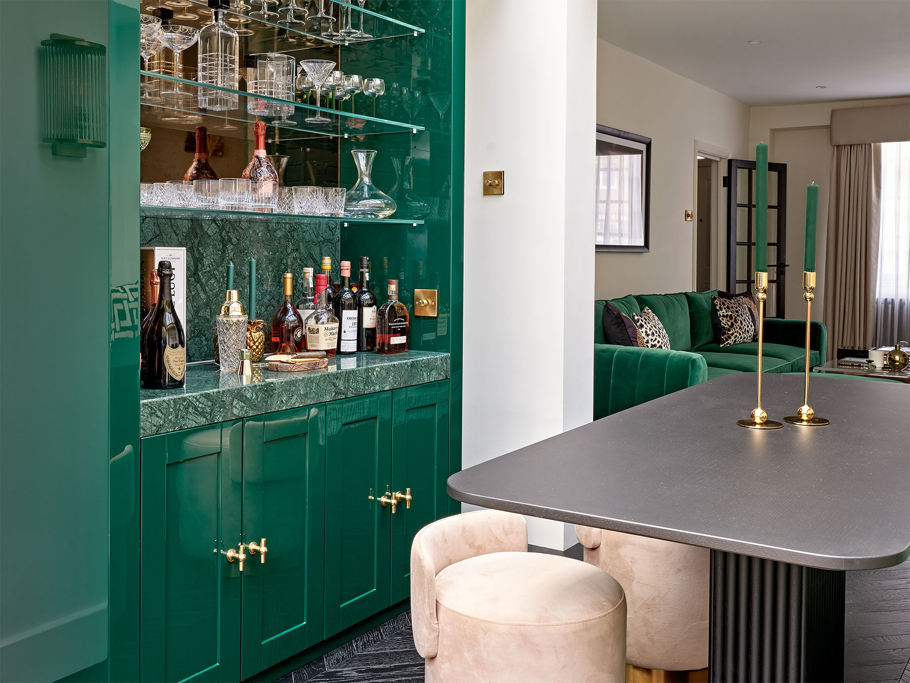 A home bar featuring a high gloss signature emerald green finish with marble top and glass detailing.