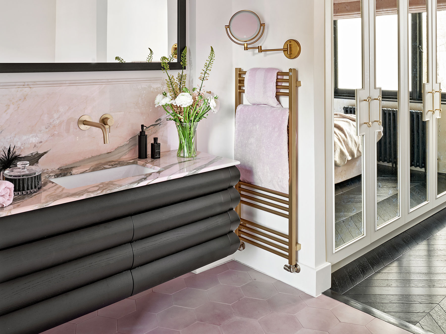 A bespoke Black Ash veneer counter hung vanity unit with concealed drawers and custom antique bronze mirror wardrobes with beading details and oak veneer interiors in a London apartment