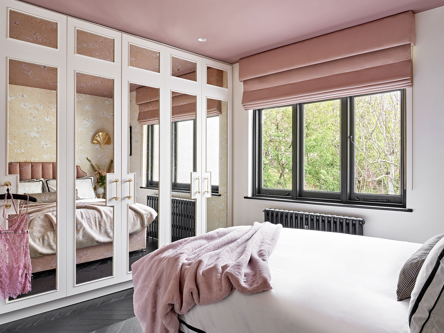 Full view of bedroom with bespoke antique bronze mirror wardrobes with beading details and oak veneer interiors